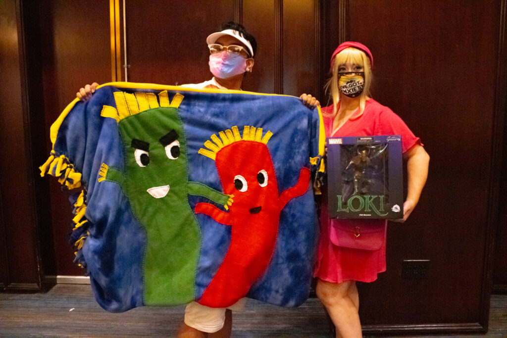 Barbie & Ken, winners of the PCAC23 Cosplay Death Match, show off their prizes - a fancy Loki figurine and a one-of-a-kind homemade blanket.